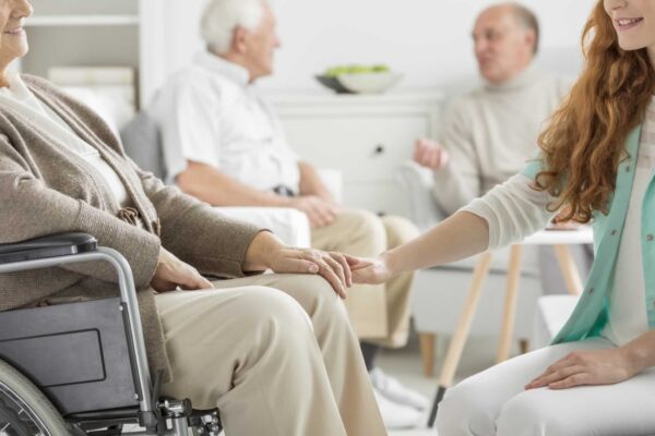 Caregiver holding elderly woman's hand in care home