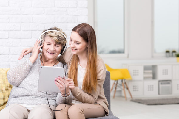 Young woman helping elderly woman with tablet