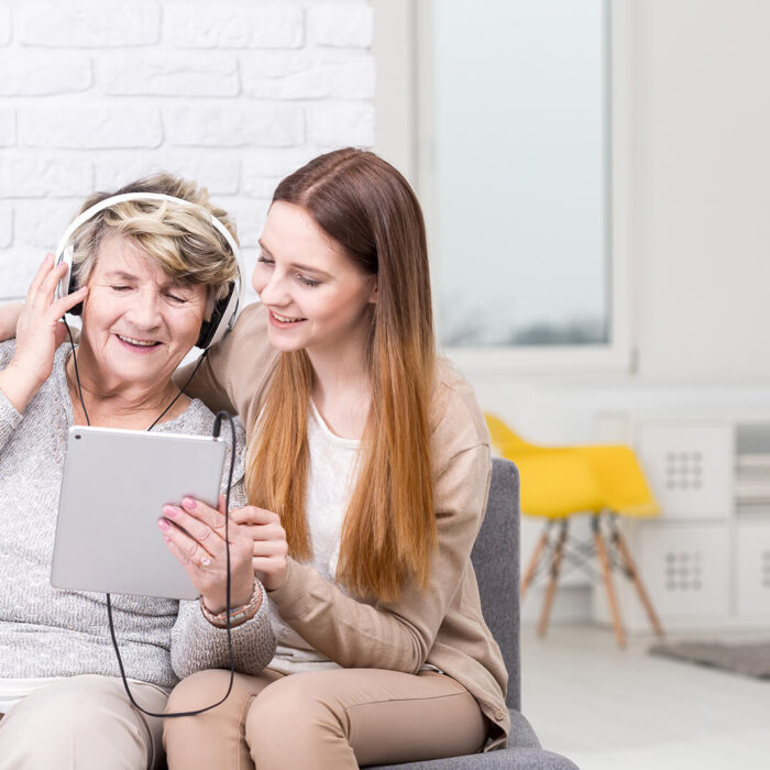 Young woman helping elderly woman with tablet