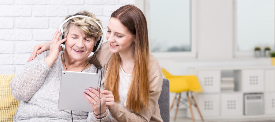 Young woman helping elderly woman with tablet
