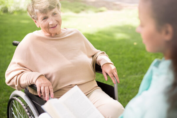 Senior woman in wheelchair talking with caregiver
