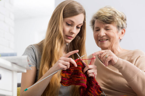 Older woman teaching younger woman to knit