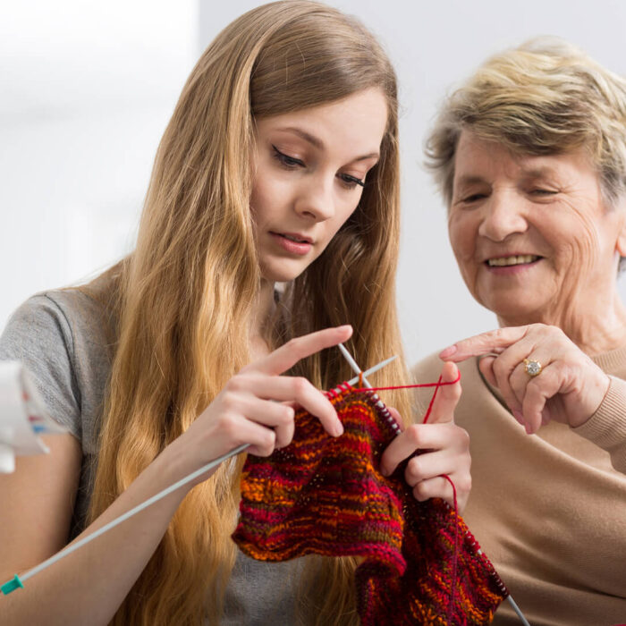 Older woman teaching younger woman to knit