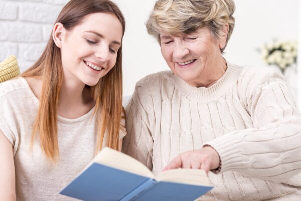 Young woman and elderly woman reading book