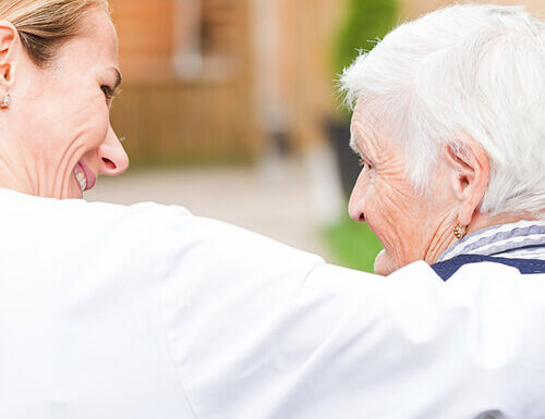 Caregiver embracing senior woman outdoors