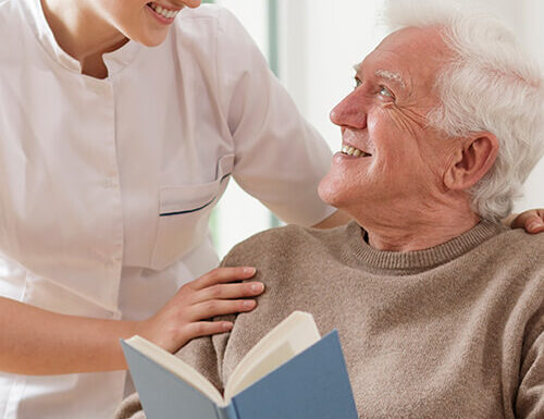 Caregiver and elderly man reading a book
