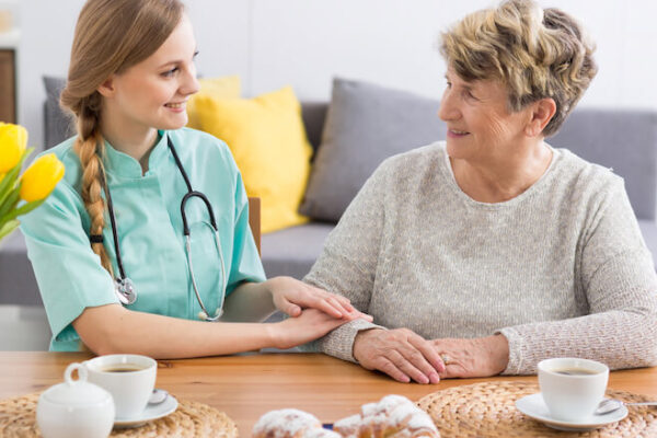 Nurse holding elderly woman's hands at table