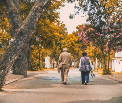 Senior couple walking down autumn tree-lined street Senior couple walking down autumn tree-lined street