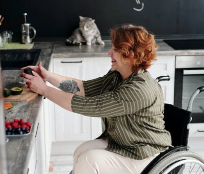 Woman in wheelchair taking photo in kitchen Woman in wheelchair taking photo in kitchen