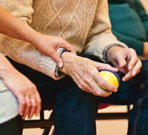 Caregiver assisting elderly person holding stress ball